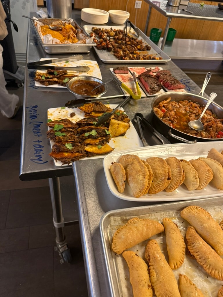 Student-prepared savory dishes and empanadas displayed in a professional kitchen