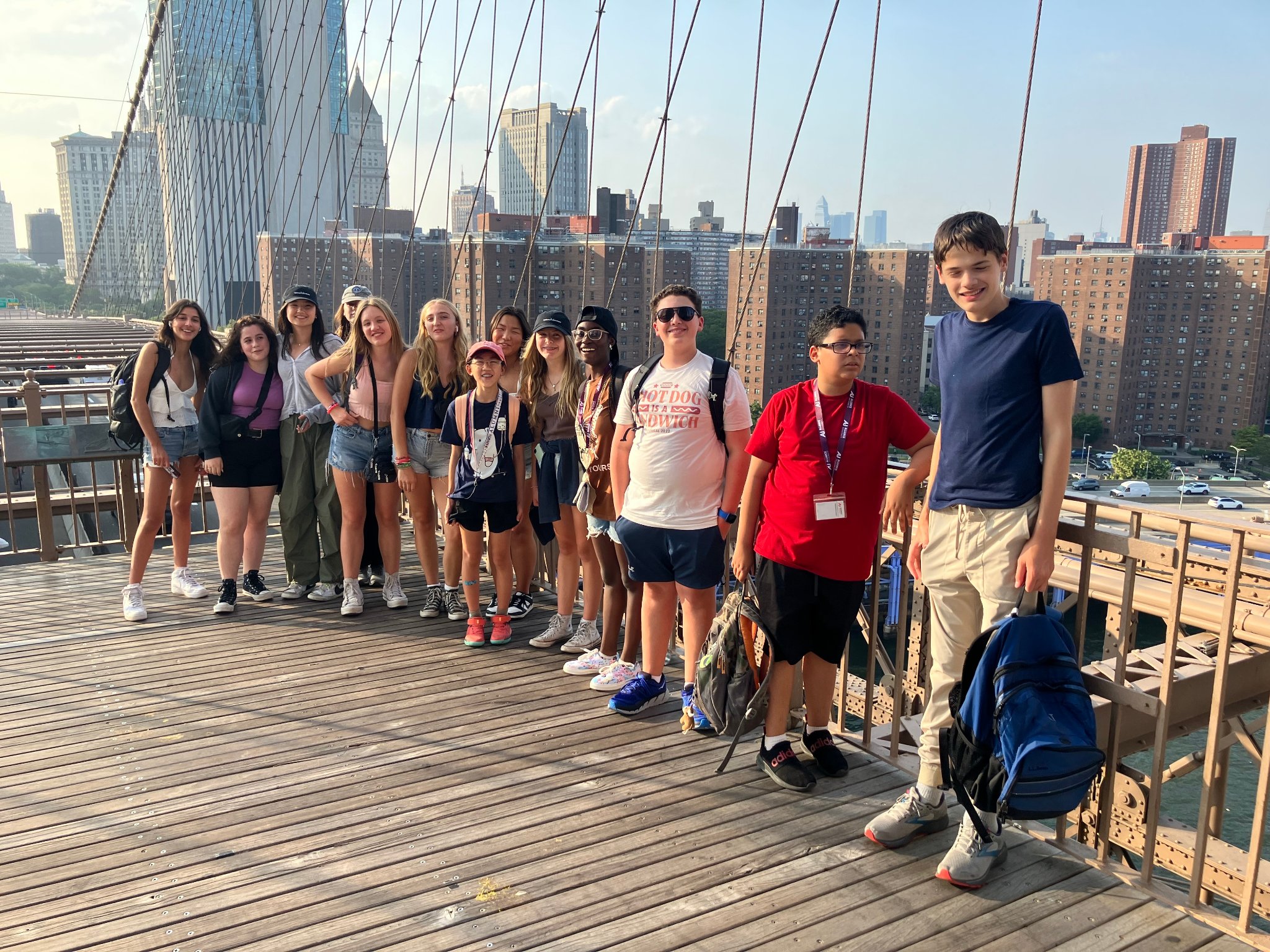Campers on the Brooklyn Bridge walkway with the NYC skyline behind them